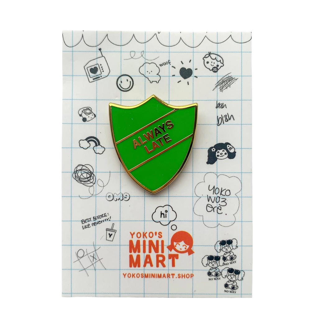 Green shield-shaped pin with 'Always Late' text on a white background with drawings